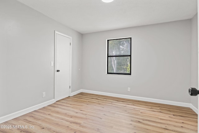 spare room featuring baseboards and wood finished floors