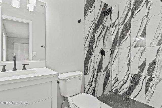 bathroom with vanity, a tile shower, and toilet