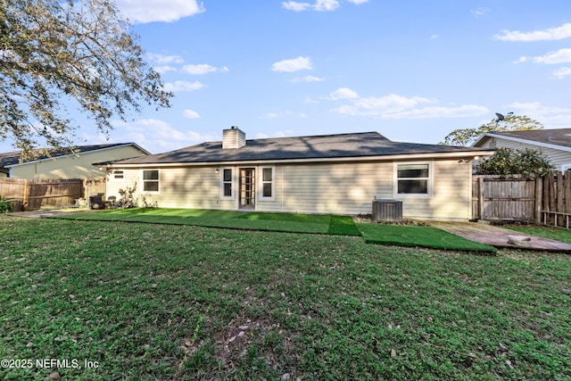 back of property featuring a fenced backyard, a lawn, a chimney, and central AC unit