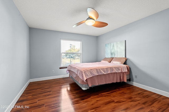 bedroom featuring ceiling fan, a textured ceiling, baseboards, and wood finished floors