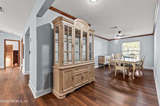 dining room with dark wood-style floors, visible vents, crown molding, and a textured ceiling