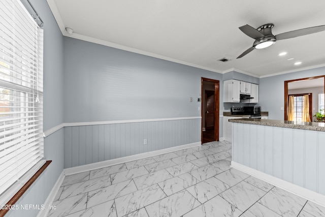 kitchen featuring marble finish floor, visible vents, range, and a wainscoted wall