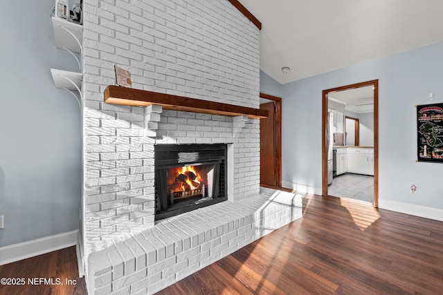 interior details featuring a brick fireplace, baseboards, and wood finished floors