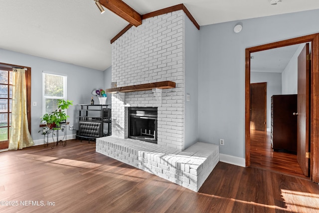 unfurnished living room featuring a brick fireplace, lofted ceiling with beams, baseboards, and wood finished floors