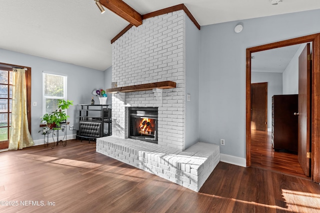 unfurnished living room with vaulted ceiling with beams, a brick fireplace, wood finished floors, and baseboards