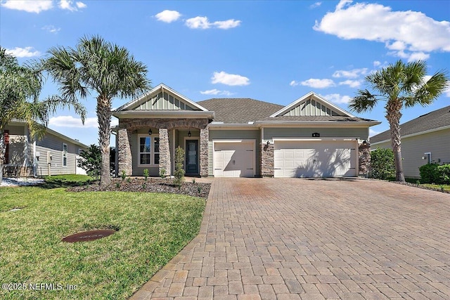 view of front of home with an attached garage, stone siding, decorative driveway, board and batten siding, and a front yard