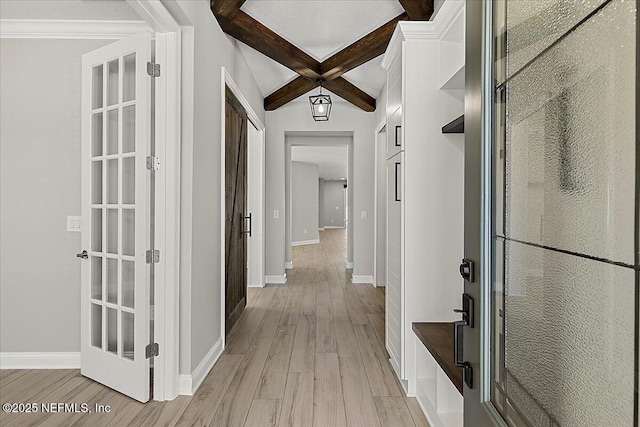 hall with beam ceiling, baseboards, and light wood finished floors