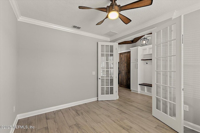 spare room with french doors, visible vents, crown molding, and wood finished floors