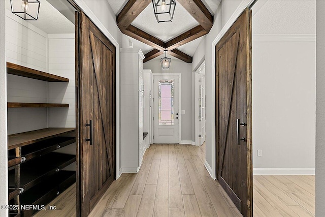 hall with light wood-style floors, a textured ceiling, baseboards, and beam ceiling