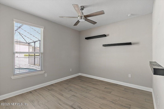 empty room featuring a ceiling fan, a textured ceiling, baseboards, and wood finished floors