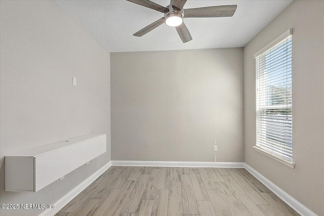 empty room featuring light wood-type flooring, ceiling fan, baseboards, and a textured ceiling