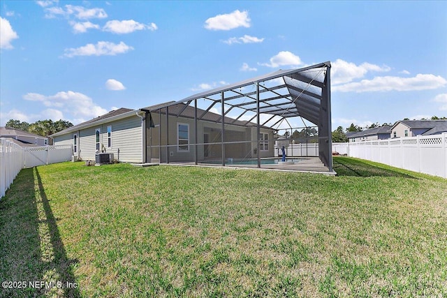 back of house with a lanai, a fenced backyard, and a lawn