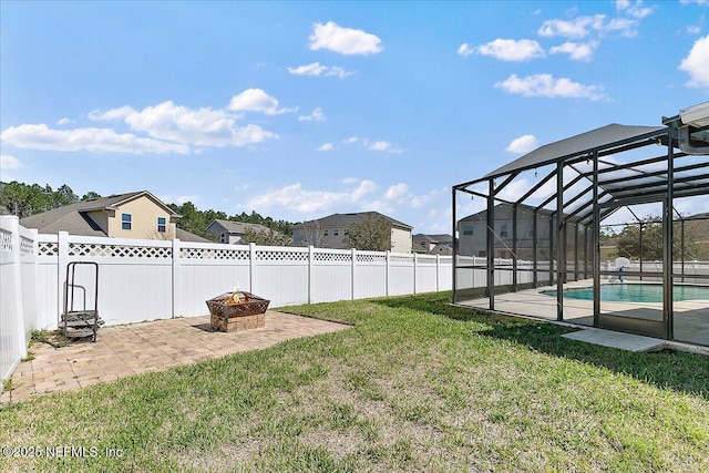 view of yard featuring a lanai, a patio area, an outdoor fire pit, and a fenced backyard