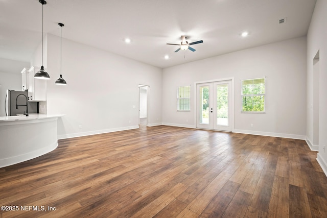 unfurnished living room with ceiling fan, visible vents, baseboards, french doors, and wood-type flooring