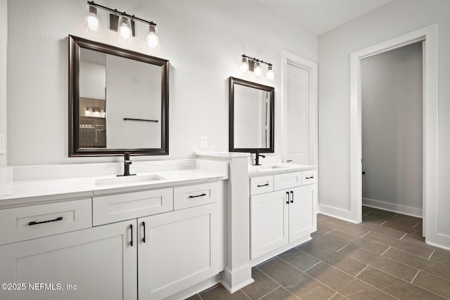 bathroom with two vanities, a sink, and baseboards