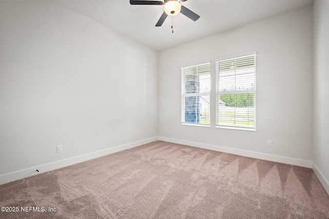 carpeted spare room featuring a ceiling fan and baseboards