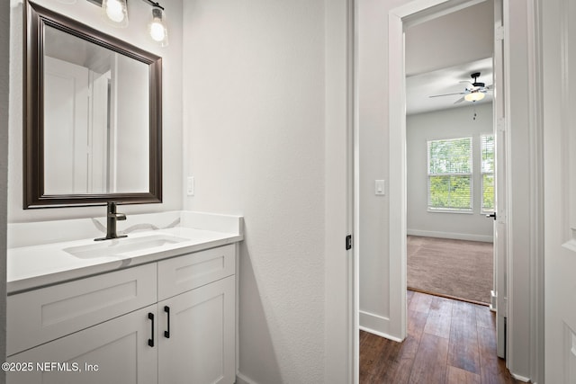 bathroom featuring ceiling fan, baseboards, wood finished floors, and vanity