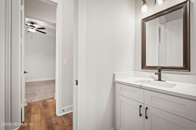 bathroom featuring ceiling fan, baseboards, wood finished floors, and vanity