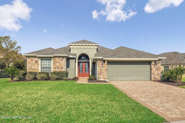 mediterranean / spanish-style home featuring decorative driveway, french doors, an attached garage, a front yard, and stone siding