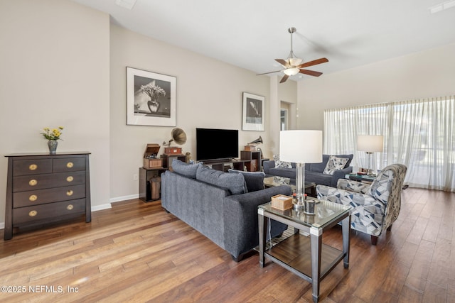 living room featuring a ceiling fan, baseboards, and wood finished floors