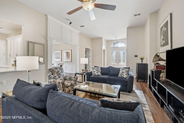 living area featuring french doors, decorative columns, visible vents, a ceiling fan, and wood finished floors