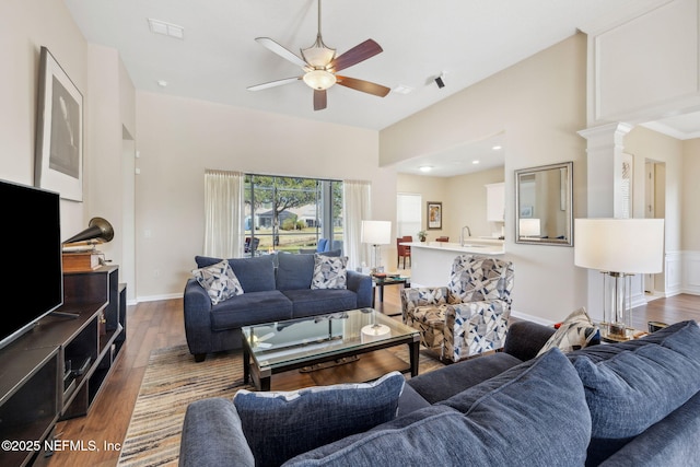 living room featuring ornate columns, visible vents, a ceiling fan, wood finished floors, and baseboards