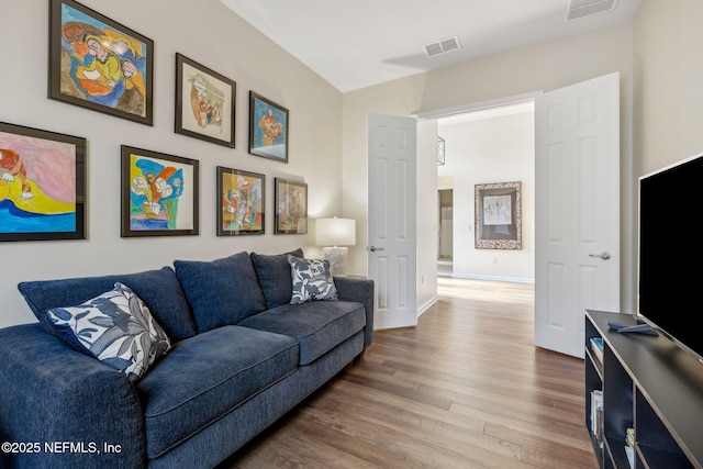 living room featuring baseboards, visible vents, and wood finished floors