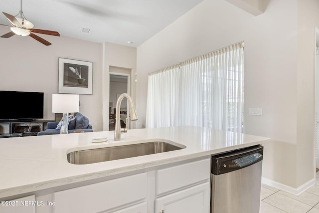 kitchen with light tile patterned floors, light countertops, stainless steel dishwasher, white cabinets, and a sink