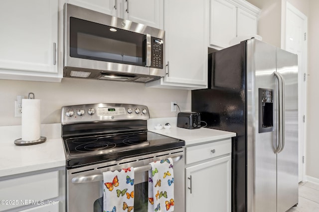 kitchen featuring white cabinetry, stainless steel appliances, and light tile patterned flooring