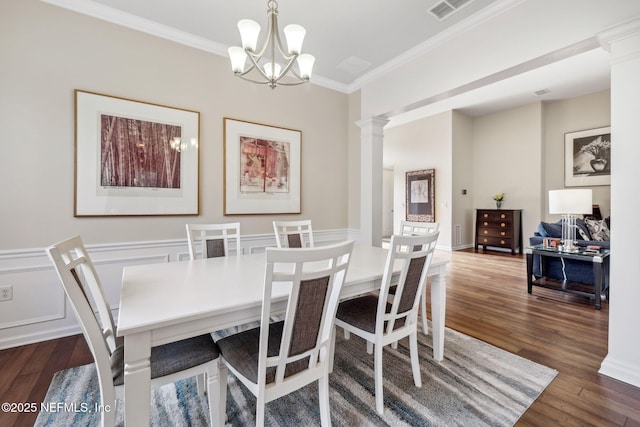 dining space featuring a wainscoted wall, ornamental molding, wood finished floors, and decorative columns