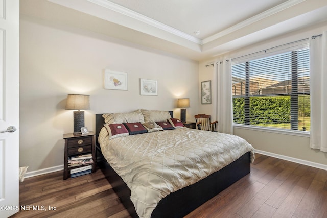 bedroom with a tray ceiling, crown molding, baseboards, and hardwood / wood-style flooring