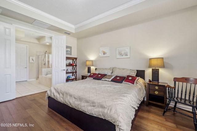 bedroom with baseboards, visible vents, wood finished floors, a tray ceiling, and crown molding