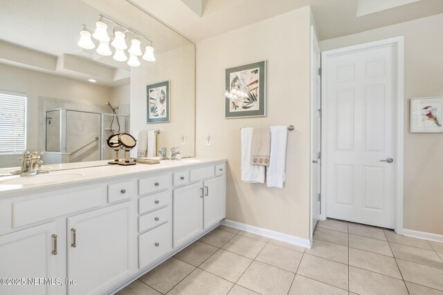 full bath featuring double vanity, a stall shower, baseboards, tile patterned flooring, and a sink