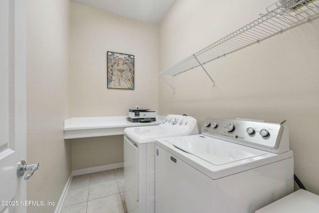 clothes washing area featuring baseboards, laundry area, light tile patterned flooring, and washer and dryer