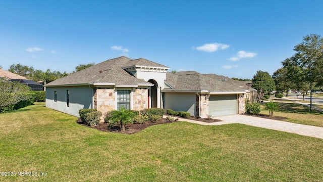 mediterranean / spanish house featuring stone siding, an attached garage, decorative driveway, a front lawn, and stucco siding