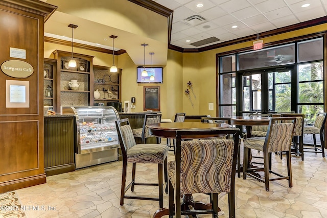 dining space featuring stone finish floor, wet bar, visible vents, and crown molding