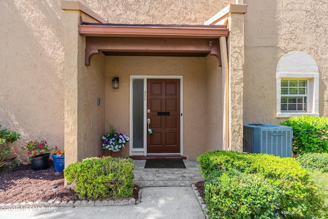 entrance to property with central air condition unit and stucco siding