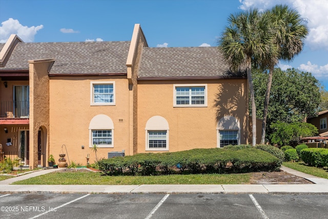 view of property with uncovered parking and central AC