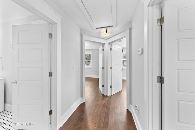 corridor featuring attic access, dark wood finished floors, and baseboards