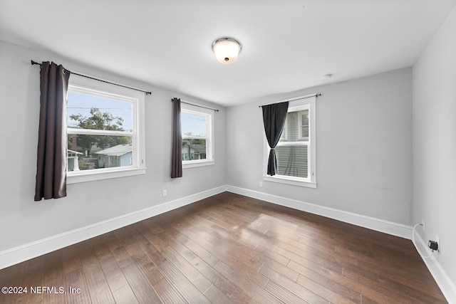 unfurnished room with dark wood finished floors and baseboards
