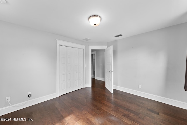 unfurnished bedroom featuring visible vents, a closet, hardwood / wood-style flooring, and baseboards