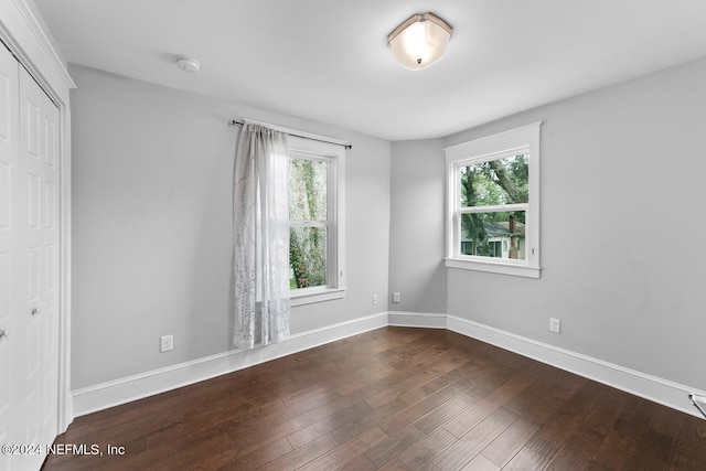 spare room with a wealth of natural light, baseboards, and wood finished floors