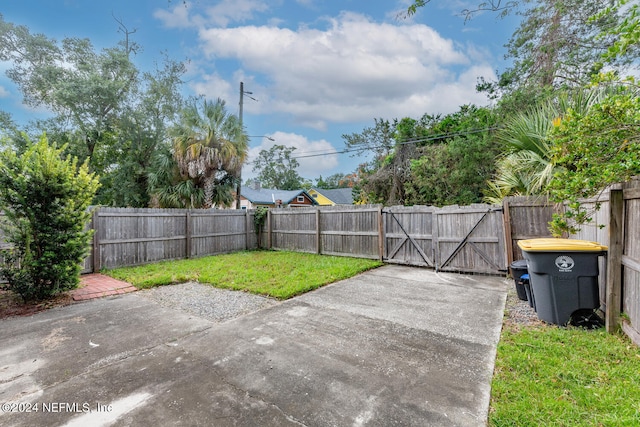 view of yard featuring a gate, a fenced backyard, and a patio