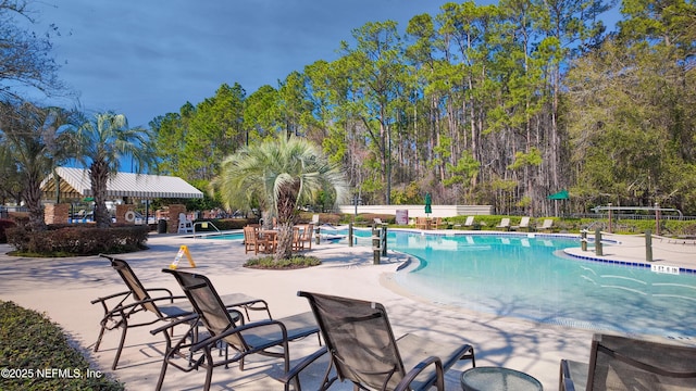 pool with a patio area and fence