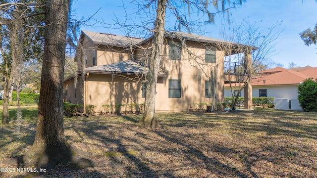 back of house with a balcony and a lawn