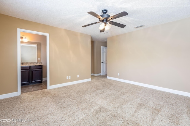 unfurnished bedroom featuring a textured ceiling, baseboards, visible vents, and light colored carpet