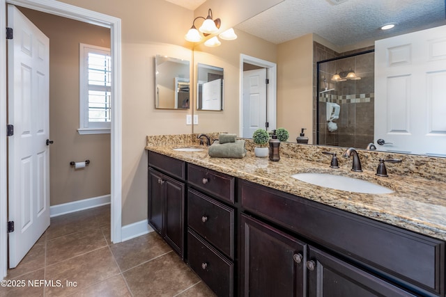 bathroom featuring a shower stall, a textured ceiling, a sink, and tile patterned floors