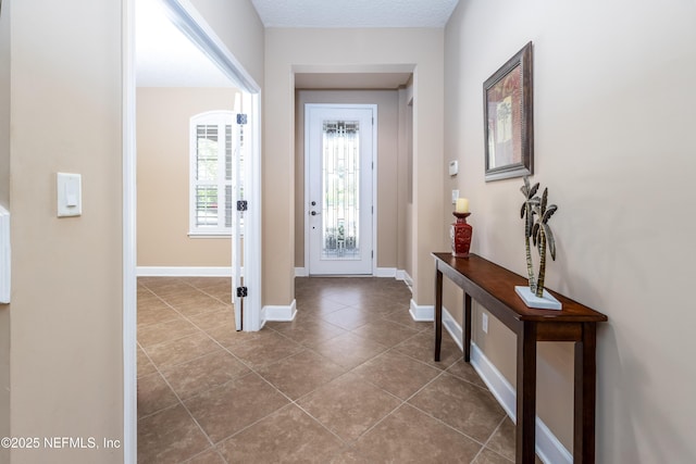 tiled entrance foyer featuring a textured ceiling and baseboards