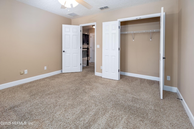 unfurnished bedroom with a closet, visible vents, carpet flooring, a textured ceiling, and baseboards