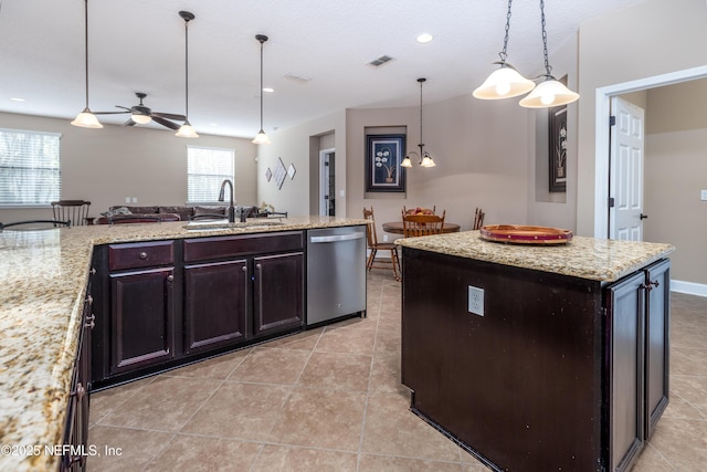 kitchen with visible vents, dishwasher, a kitchen island, light stone counters, and a sink